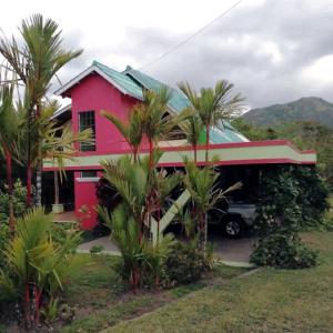 una casa rossa con una macchina parcheggiata di fronte di Residencia entera Valle de Anton, El Valle de Lily a El Valle de Antón