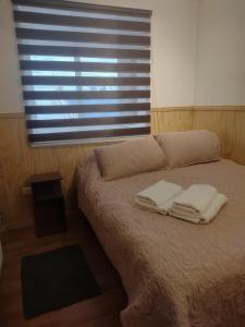 ein Schlafzimmer mit einem Bett mit zwei Handtüchern darauf in der Unterkunft Departamentos Kitkaika in Punta Arenas