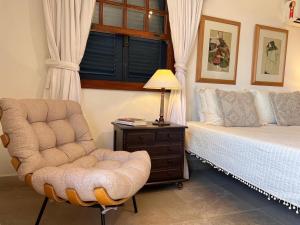 a bedroom with a bed and a chair and a lamp at Pousada Blanca Mar in Búzios