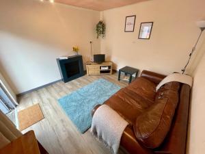 a living room with a brown leather couch and a television at Lovely 3BD Home in the Heart of Morton in Morton