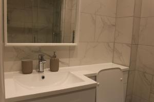 uma casa de banho branca com um lavatório e um espelho em High-End Central Luton Studio - Ideal for Airport! em Luton