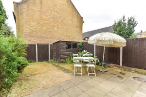 a patio with a table and an umbrella at Modern 4 bedroom Terraced House by the Thames in London
