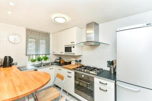 a kitchen with white cabinets and a wooden table at Modern 4 bedroom Terraced House by the Thames in London