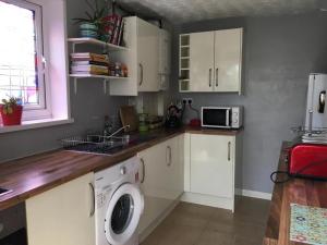 a kitchen with a washing machine and a microwave at Wonderfully Cosy 3BD Home in the Heart of Cornwall in St Austell