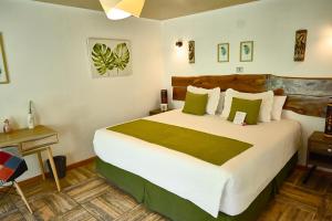 a bedroom with a large white bed with green pillows at Hare Nua Hotel Boutique in Hanga Roa