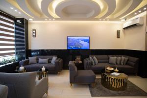 a lobby with couches and a tv on a ceiling at TAJ Hotel in Aqaba