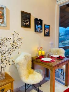 a dining room with a table and two white chairs at Chalés Vale das Araucárias Bairro dos Onças in Gonçalves