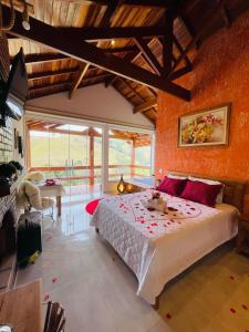 a bedroom with a large bed with red pillows at Chalés Vale das Araucárias Bairro dos Onças in Gonçalves