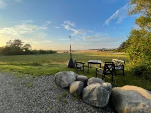 a picnic table and chairs in a field with rocks at Room 6 - Hawkraft Kulturhotel in Vestervig