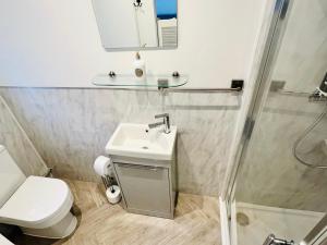 a bathroom with a sink and a toilet and a mirror at The Terrace - Tankerton in Kent