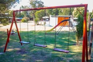 a swing set in a park with a playground at La Casona Cabañas in Villa Ciudad Parque