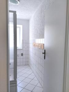 a white tiled bathroom with a shower and a door at Usedoms Kleines Ostseeglück #1 in Peenemünde bis 4 Personen, Zuganreise möglich in Peenemünde