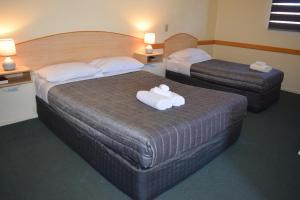 two beds in a hotel room with towels on them at Warwick Vines Motel in Warwick