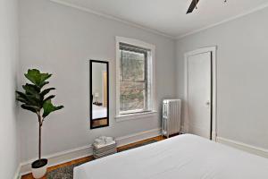 a white bedroom with a bed and a potted plant at Deluxe 1BR Apartment in Ravenswood - Campbell 3 in Chicago
