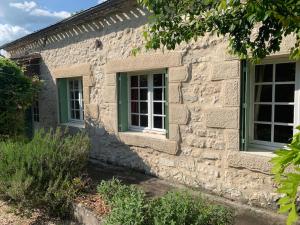 een stenen huis met twee ramen aan de zijkant bij La Maison Pourpre in Vélines