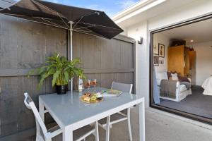 einen Tisch und Stühle auf einer Terrasse mit Sonnenschirm in der Unterkunft Matamata Lodge in Matamata