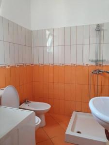 een oranje en witte badkamer met een toilet en een wastafel bij Cozy Apartment near Ohrid Lake in Pogradec