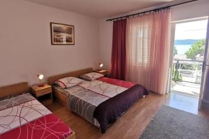 a bedroom with two beds and a large window at Apartments by the sea Zivogosce - Mala Duba, Makarska - 18626 in Igrane