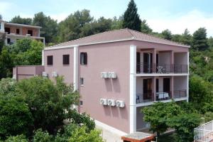 ein rosafarbenes Gebäude mit Bäumen im Hintergrund in der Unterkunft Apartments by the sea Loviste, Peljesac - 18656 in Lovište
