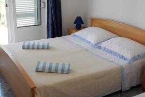 a bed with two blue and white pillows on it at Apartments by the sea Loviste, Peljesac - 18656 in Lovište