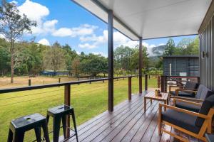 porche cubierto con sillas y vistas a un campo en Contained in Nimbin Accommodation, en Nimbin