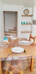 mesa de comedor con platos y reloj en la pared en Thuir, Charmante Maison T2 Climatisée en Thuir