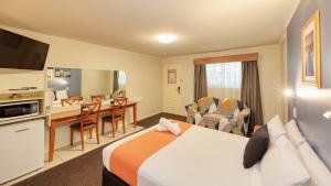 a hotel room with a bed and a kitchen and a desk at Best Western Caboolture Gateway Motel in Caboolture