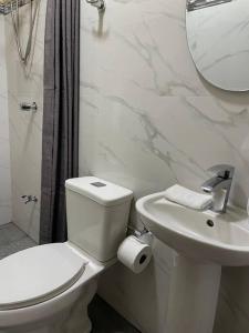 Baño blanco con aseo y lavamanos en Airport SJO Residence - Edward & Familia Inn, en Alajuela