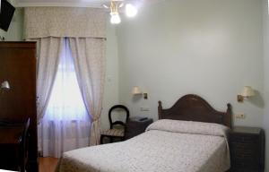 1 dormitorio con 1 cama y una ventana con cortinas en Hotel Chipén, en Vigo