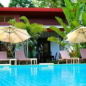 a pool with chairs and umbrellas next to a house at Arthaya Villas - SHA Extra Plus in Ko Lanta