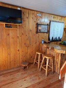 Zimmer mit Holzwänden und einer Bar mit Hockern in der Unterkunft Sítio Cabanas da Lu in Canela