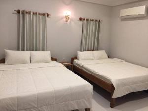 two beds in a room with white sheets at Treuy Koh Bungalow in Kampot