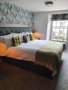 a bedroom with a large bed with green pillows at The Coach and Horses in Hexham