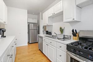 cocina con armarios blancos y nevera de acero inoxidable en 1BR Simple & Roomy Apartment in Evanston - Hinman S3, en Evanston