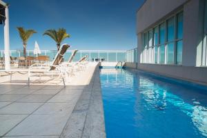 a swimming pool with lounge chairs next to a building at SMART Flats - Decorado Superior - 11º andar - Esplanada - Saint Moritz in Brasilia