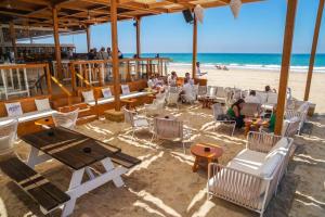 un bar sulla spiaggia con persone sedute a tavoli e sedie di AGUA Cabaña con jardín y parking privado Chiclana a Chiclana de la Frontera