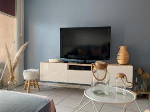 una sala de estar con TV y un jarrón sobre una mesa en Le tout à pied!, en Ciboure