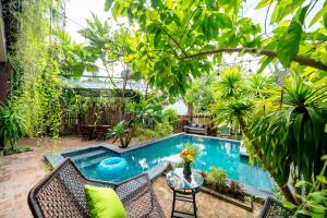 a swimming pool in a garden with a table and chairs at Olala An Bang Villa in An Bàn (2)