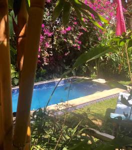 a swimming pool in a garden with pink flowers at Red Palms in Blahbatu