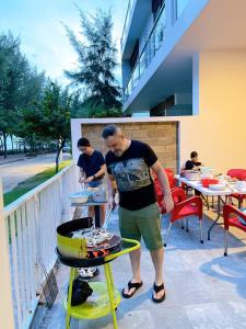 Ein Mann, der Essen auf einem Grill auf einer Terrasse kocht in der Unterkunft Villa Zenna Long Hải - Mimosa 611 View Biển in Long Hải