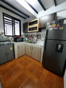 a kitchen with a black refrigerator and a wooden floor at APARTAMENTO CON VISTA A LAS MONTAÑAS CAPACIDAD 6 PERSONAS SECTOR VILLAMARIA in Villamaría