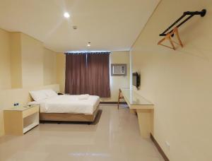 Habitación de hotel con cama y ventana en Kaizen Suites en Manila