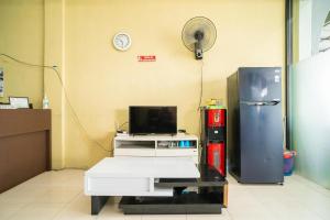 a room with a refrigerator and a desk with a fan at RedDoorz Syariah @ Jalan Bukit Kaminting 2 in Palangkaraya