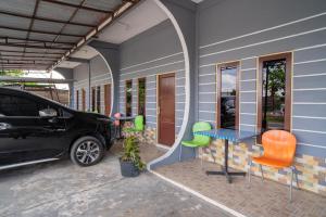 a car parked next to a house with a table and chairs at RedDoorz Syariah @ Jalan Bukit Kaminting 2 in Palangkaraya