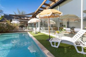 a house with a swimming pool with two chairs and an umbrella at Poolside Paradise Mount Eliza in Mount Eliza