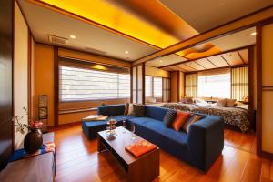 a living room with a blue couch and a bed at Kanazawa Hyakurakusou in Kanazawa
