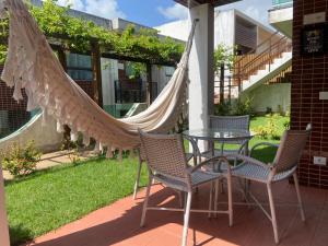 una hamaca en un patio con sillas y mesa en Néctar de Enseada apart a 50mt da praia Cabo de Santo Agostinho, en Cabo de Santo Agostinho
