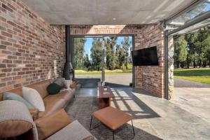 a living room with a couch and a tv in a brick wall at Robinsons Run The ultimate luxury country retreat in Kangaroo Valley