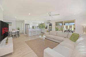 a living room with a white couch and a kitchen at Maroochy Magic Family Coastal Getaway in Maroochydore