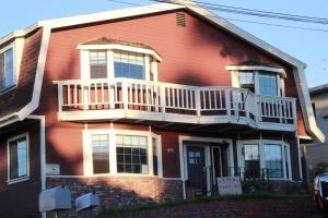a red house with a porch and a balcony at Ocean's Breeze, 4/bed, 3/ba, Game Room. Sleeps 10! in Morro Bay